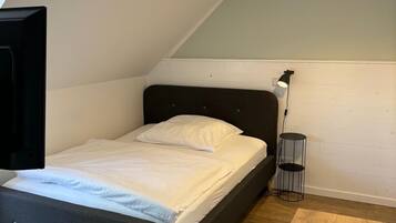 Un dormitorio con cama, escritorio, lámpara y luz en el techo.