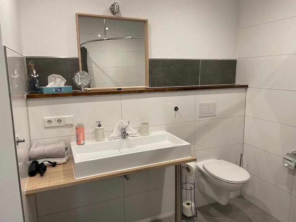 Ein modernes Badezimmer mit Waschbecken, Spiegel und Toilette.