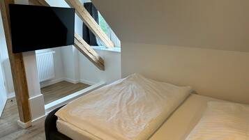 Een slaapkamer met een bed, een raam met uitzicht en een aan de muur bevestigde televisie.