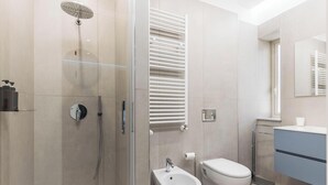Ein modernes Badezimmer mit einer Duschkabine, einer Toilette, einem Waschbecken und einem Handtuchhalter.