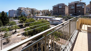 Ein Balkon mit Blick auf eine Stadtansicht, darunter mehrstöckige Gebäude und ein Parkplatz.