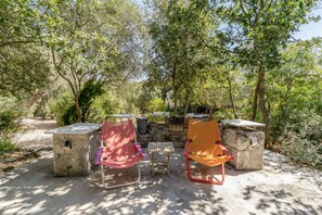 An outdoor seating area with stone tables and chairs, surrounded by trees. - Villa Manghisi with Private Pool, Wi-Fi and Air Conditioning (Noto)