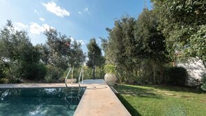 A swimming pool with a concrete deck, surrounded by greenery and trees. - Villa Manghisi with Private Pool, Wi-Fi and Air Conditioning (Noto)
