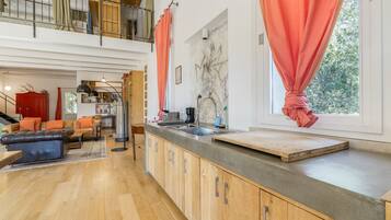 Une cuisine moderne dotée d’un grand îlot central, de meubles en bois et offrant une vue sur l’extérieur grâce à une fenêtre.