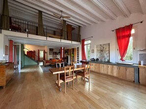 A spacious loft-style living area with a dining table, chairs, a kitchen area, and a staircase leading to an upper level. - Villa Manghisi with Private Pool, Wi-Fi and Air Conditioning (Noto)