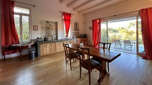 A spacious kitchen with wooden cabinets, a dining area with a table and chairs, and large windows with red curtains. - Villa Manghisi with Private Pool, Wi-Fi and Air Conditioning (Noto)