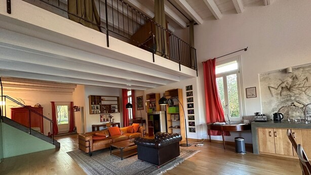 A spacious living area with a high ceiling, a staircase, a sofa set, a bookshelf, and a kitchen area. - Villa Manghisi with Private Pool, Wi-Fi and Air Conditioning (Noto)