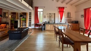 A spacious living area with a high ceiling, a dining table, and a kitchen area with red curtains. - Villa Manghisi with Private Pool, Wi-Fi and Air Conditioning (Noto)