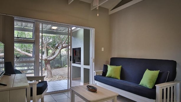 A living room with a sofa, a coffee table, and a dining area with a table and chairs.