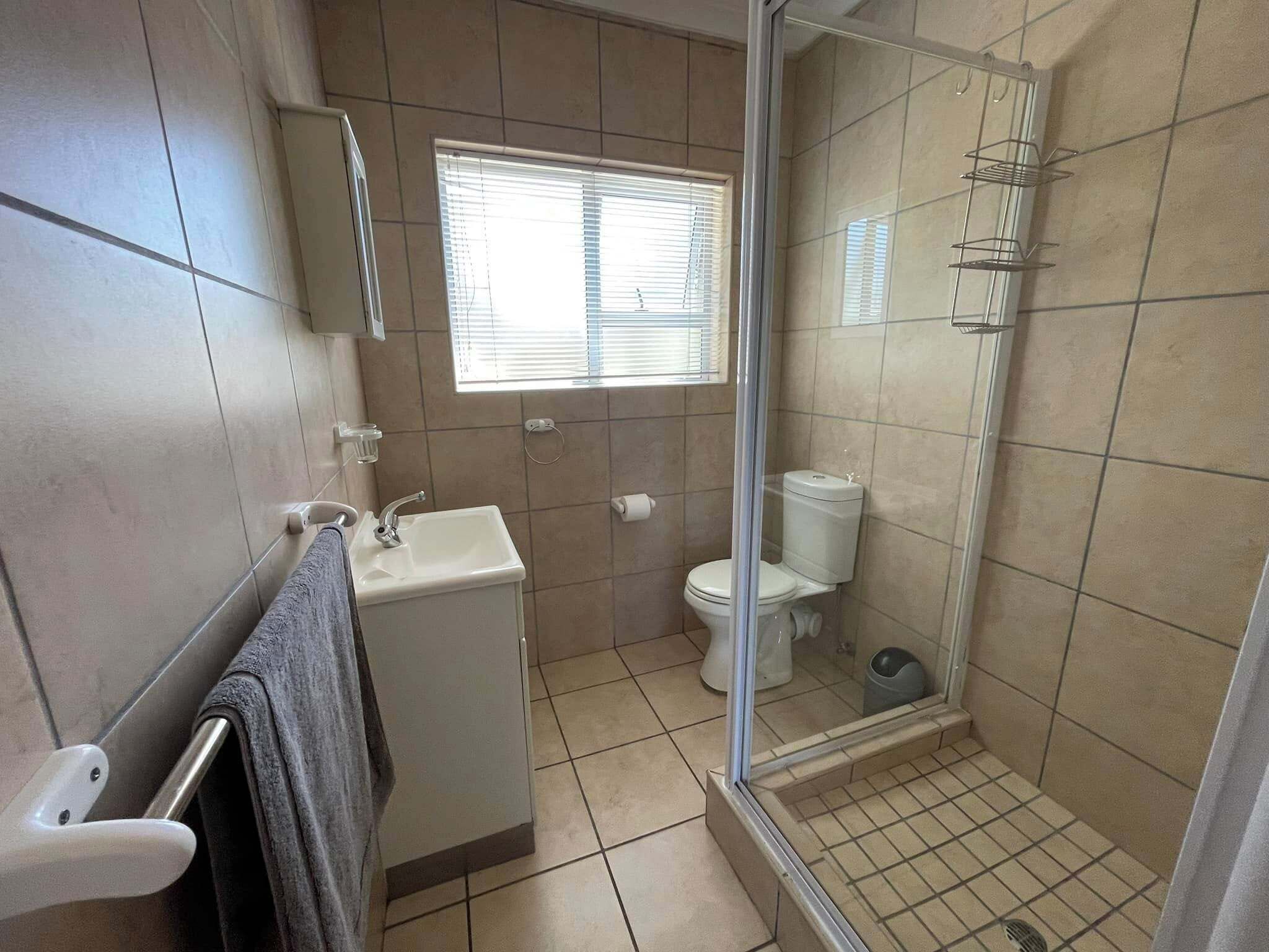 A bathroom with a sink, toilet, and shower area.