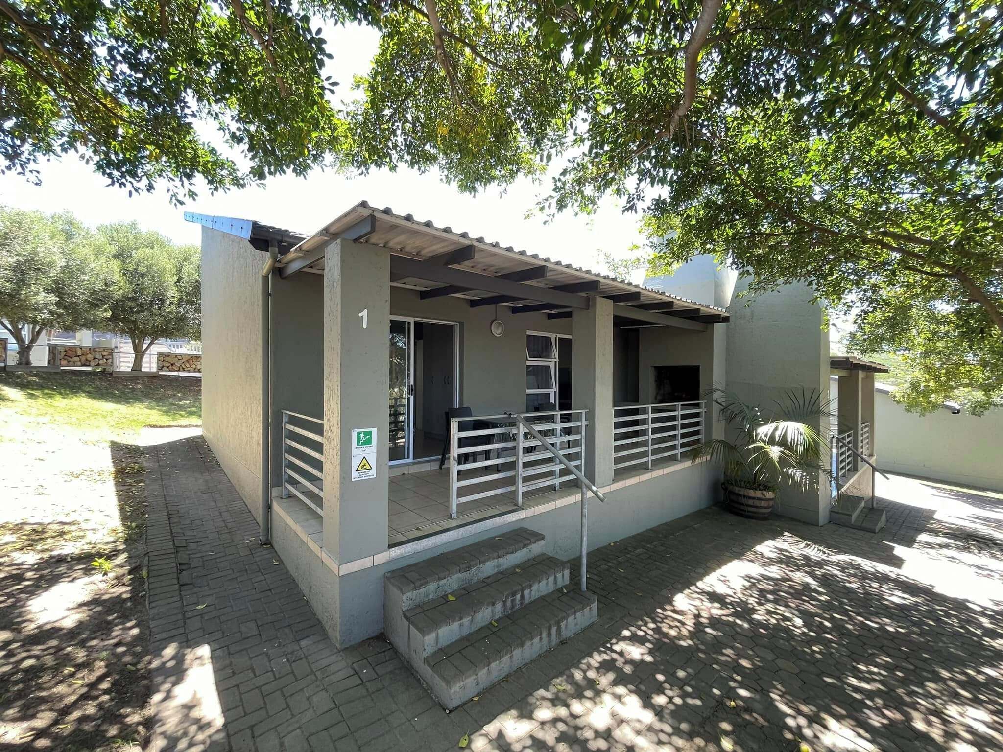A small building with a covered porch, a staircase leading to the entrance, and a sign indicating a wheelchair-accessible entrance.