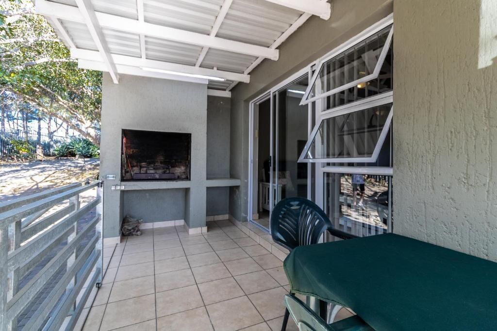 Un patio couvert comprenant un barbecue, une chaise et une table.
