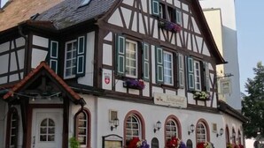 A traditional half-timbered building with a white facade, multiple windows with shutters, and a sign indicating it is a restaurant. - Hotel Schützenhof mit Wellness  (Buerstadt)