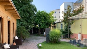 A courtyard with a paved walkway, outdoor furniture, and greenery. - Hotel Schützenhof mit Wellness  (Buerstadt)