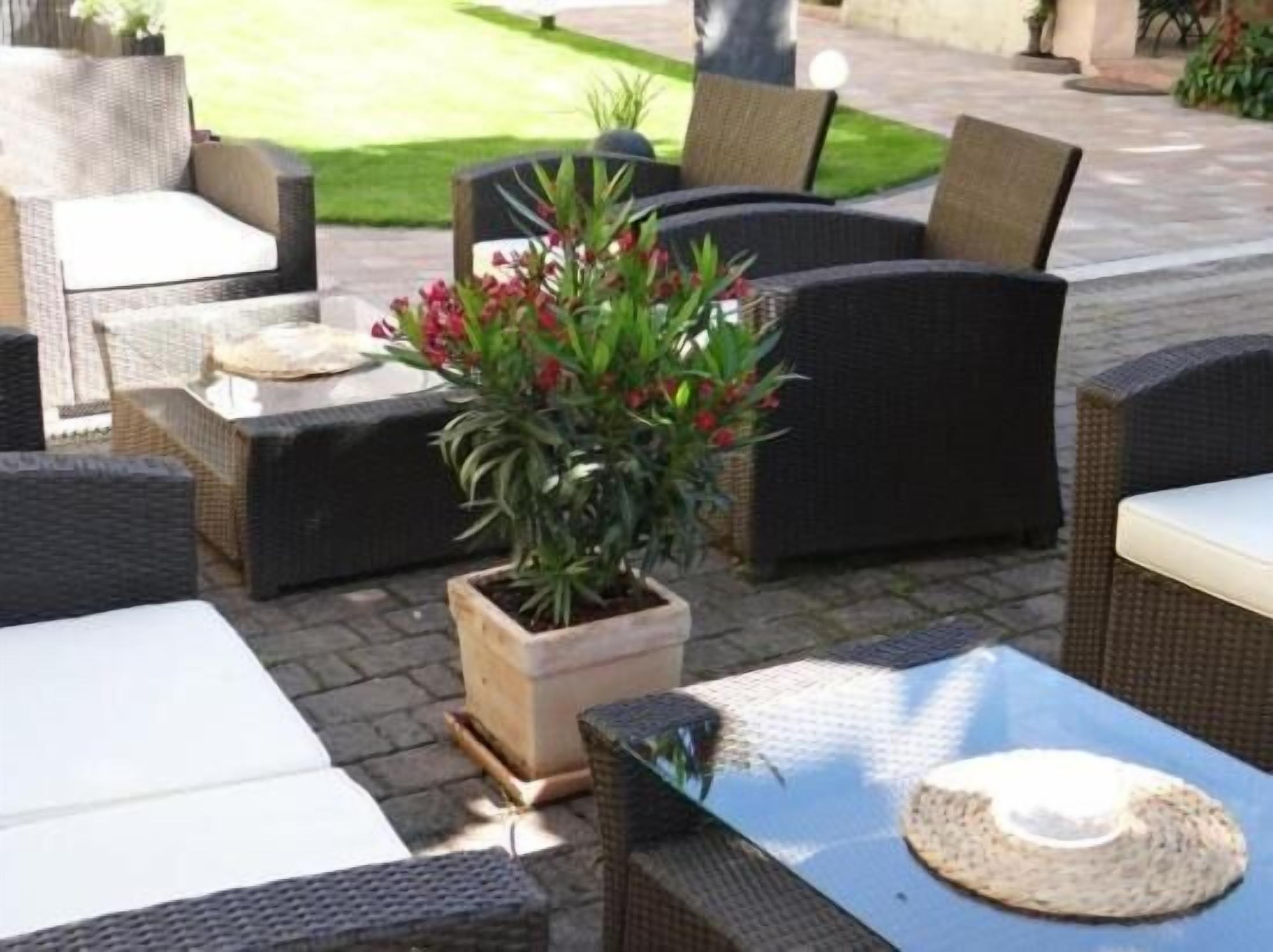 Outdoor wicker furniture, a potted plant, and a table with a hat.