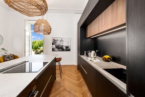 Eine moderne Küche mit einer großen Kochinsel, dunklen Schränken und einer Pendelleuchte.