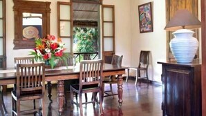 A dining area with a wooden table, chairs, a vase of flowers, and a ceiling fan.