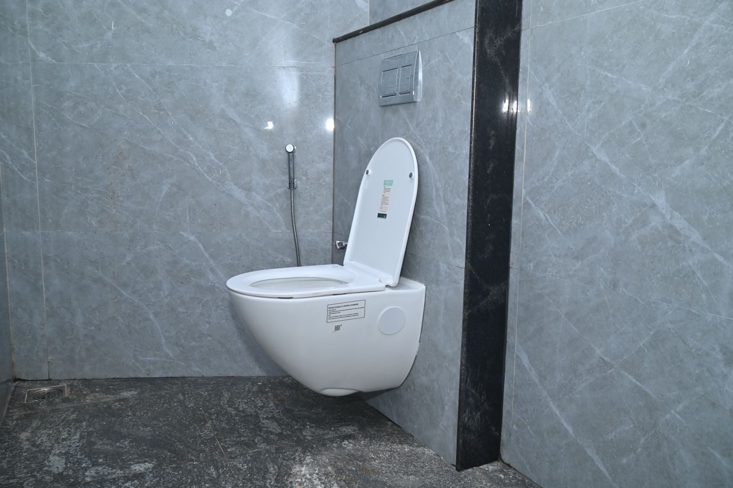 A modern bathroom with a white toilet, a shower, and a marble floor.