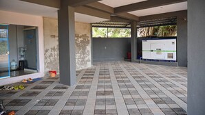 An indoor area with tiled flooring, a water dispenser, and a Koel air conditioning unit. - AES Residency (Bhatkal)