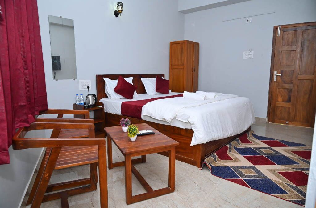 A hotel room with a bed, wooden furniture, a mirror, a wardrobe, and a patterned rug.