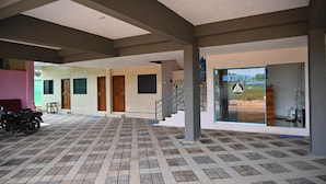 A reception area with a staircase, a reception desk, and a motorcycle parked outside. - AES Residency (Bhatkal)