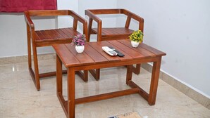 A wooden table with two chairs, a remote control, and two potted plants. - AES Residency (Bhatkal)