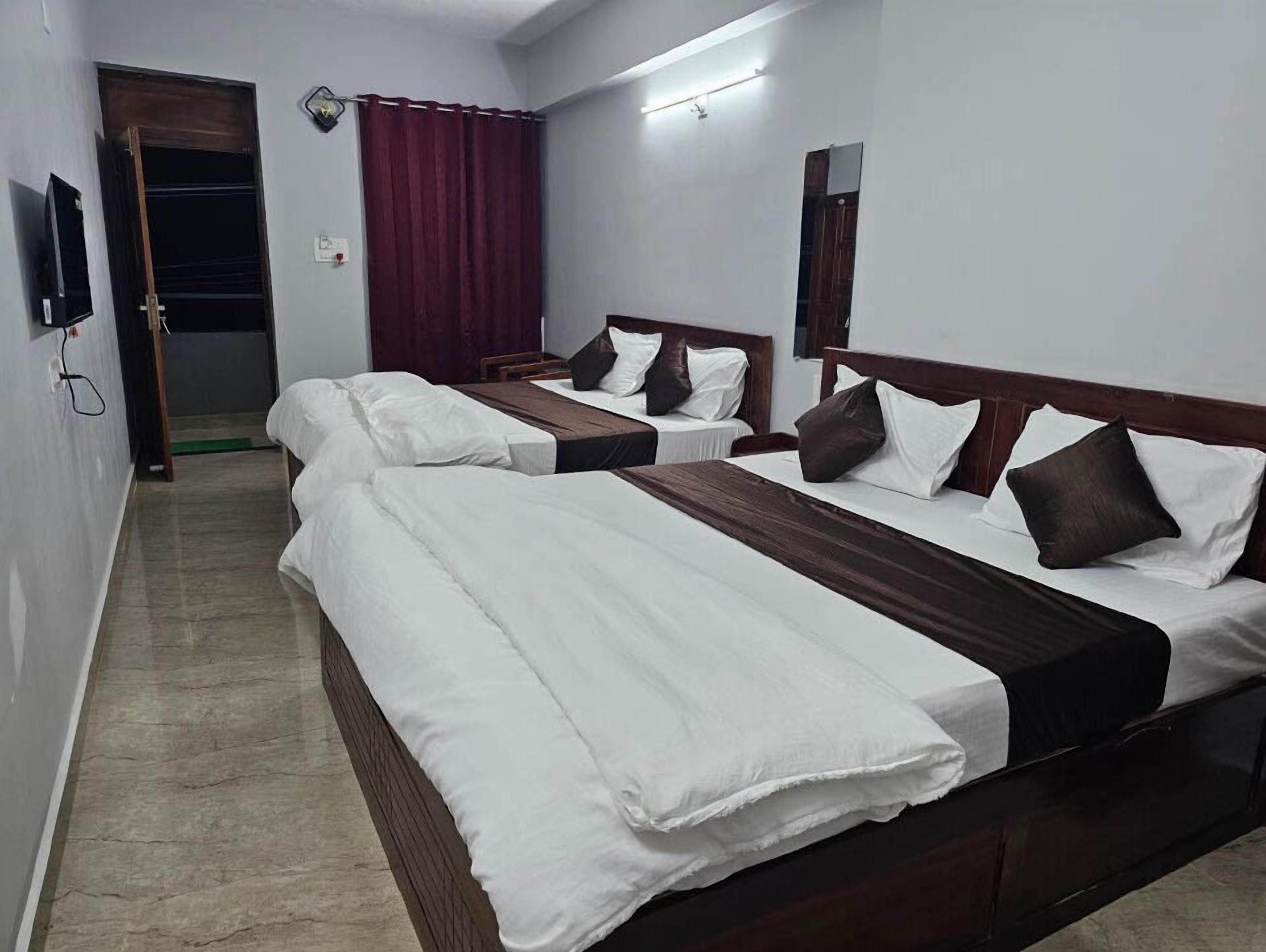 A hotel room with three beds, a mirror, and a door.