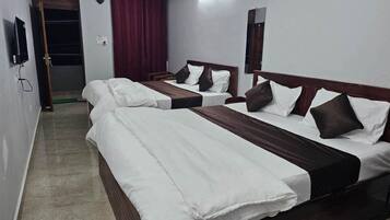 Ein Hotelzimmer mit drei Betten, einem Spiegel und einer Tür.