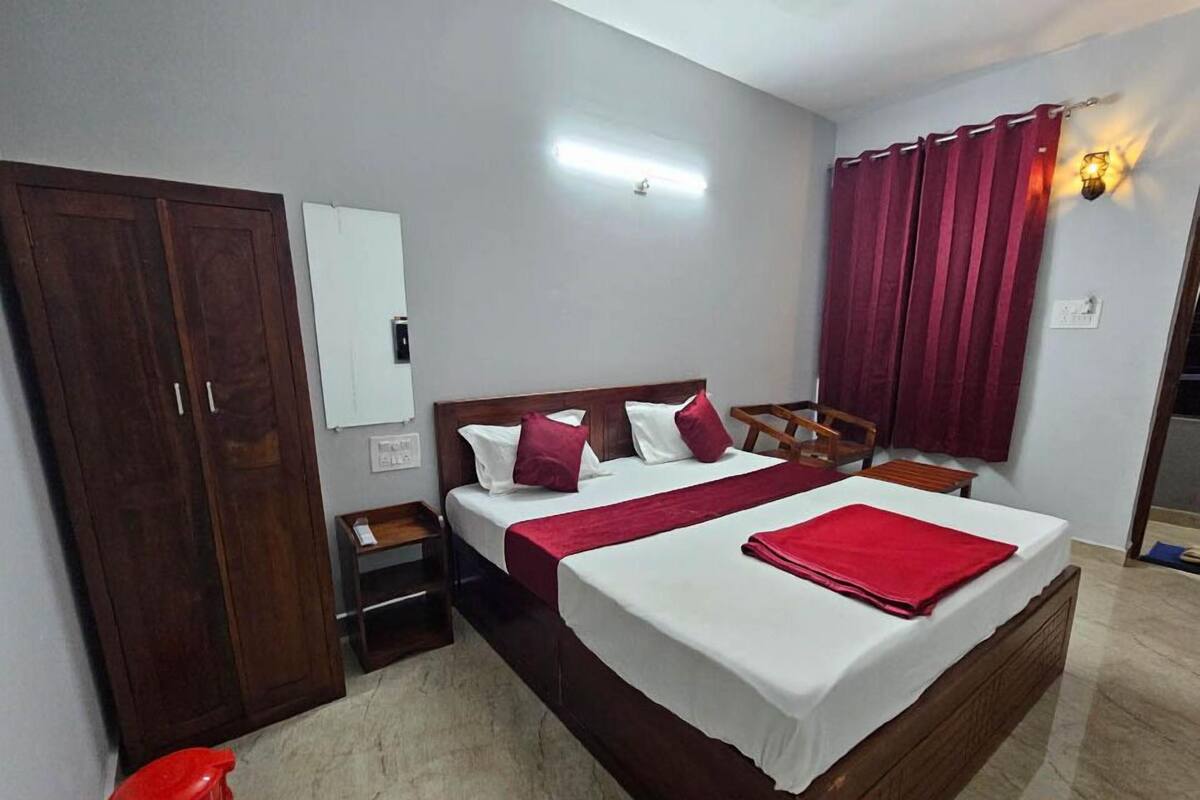 Ein Hotelzimmer mit einem großen Bett, einem Kleiderschrank, einem Nachttisch und einem roten Vorhang.