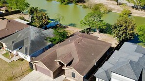A residential area with houses, a pond, and surrounding greenery. - Casa Granero, Waterfront 3BD/2BA w/ Private Yard! (Brownsville)