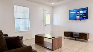 A living room with a couch, coffee table, TV, and a wooden cabinet. - Casa Granero, Waterfront 3BD/2BA w/ Private Yard! (Brownsville)