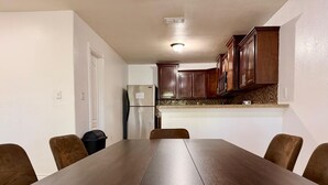 A dining area with a wooden table and chairs, a kitchen with wooden cabinets, and a refrigerator. - Casa Granero, Waterfront 3BD/2BA w/ Private Yard! (Brownsville)