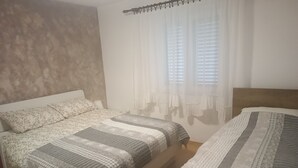 A bedroom with two beds, a window with sheer curtains, and a headboard. - Apartment Gea (Rovinj)