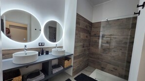 A modern bathroom with two sinks, a mirror, and a shower.