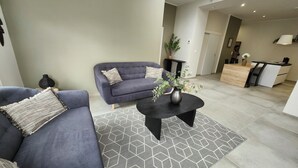 A modern living room with a sofa, coffee table, and a geometric rug.
