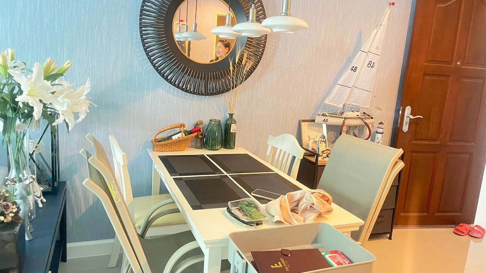 A dining area with a table, chairs, a mirror, a sailboat model, and a door.