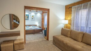 Un dormitorio con cama, cabecera de madera, espejo redondo, mesita de noche, lámpara y vista a una escalera.