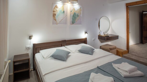 Un dormitorio con cama, mesitas de noche, espejo y obras de arte en la pared.