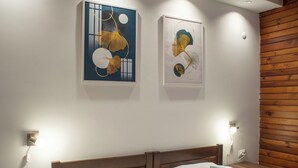 Un dormitorio con cabecera de madera, dos camas, ropa de cama blanca y una obra de arte colgada en la pared.