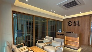 A hotel reception area with a reception desk, seating area, and a large window with a view. - 611 Hotel (Phetchaburi)