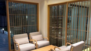 A modern indoor seating area with cushioned chairs and a wooden table, large sliding glass doors, and recessed ceiling lighting. - 611 Hotel (Phetchaburi)