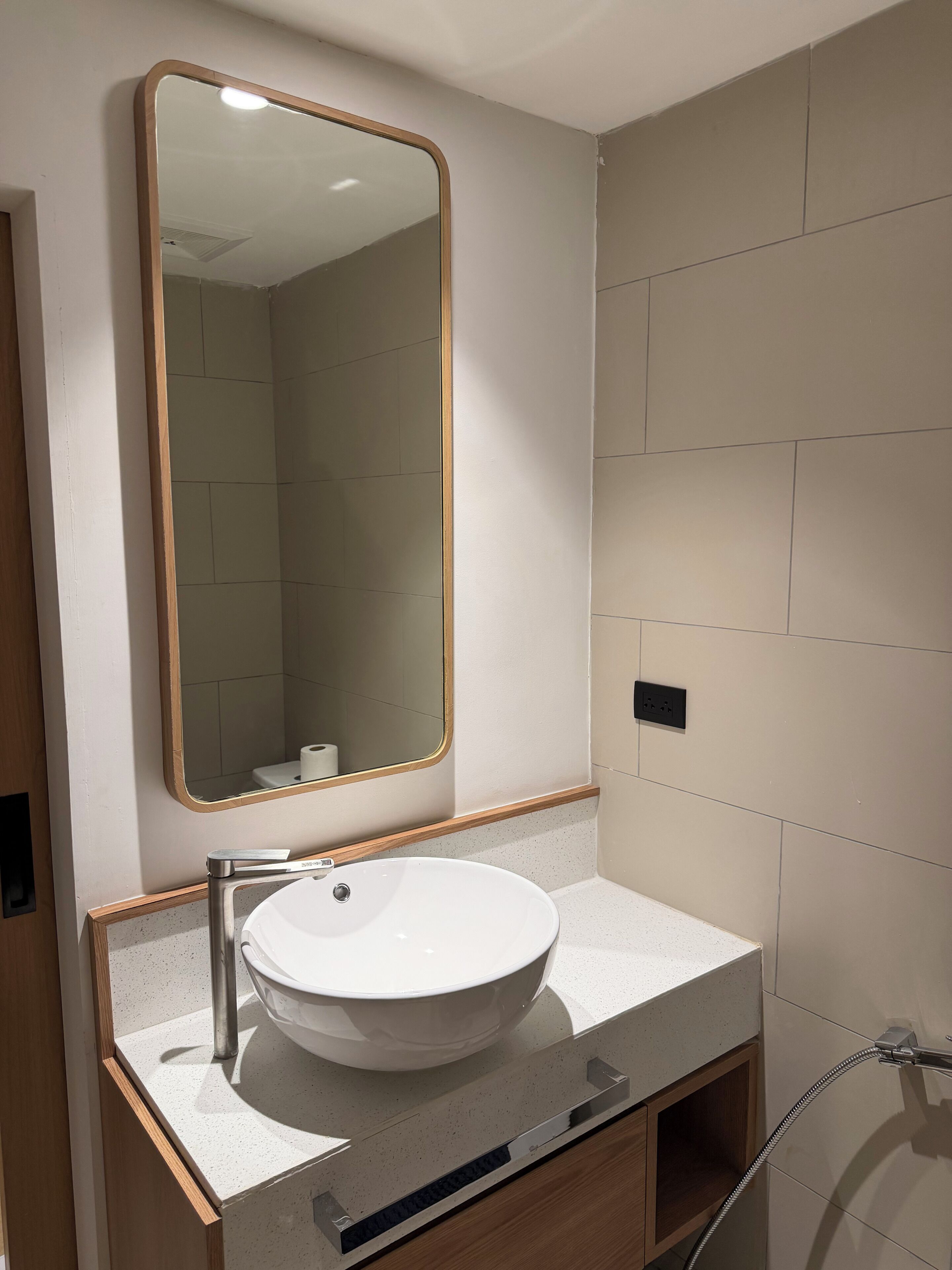 A bathroom with a white sink, a mirror with a wooden frame, and a shower area.
