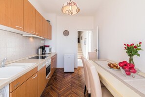 Eine moderne Küche mit Holzausstattung, Spülmaschine, Mikrowelle und Kaffeemaschine. Ein Essbereich mit Tisch, Stühlen und einer Vase mit roten Blumen.