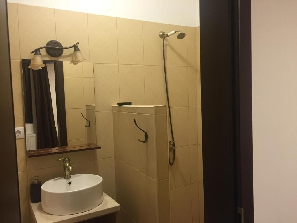 Ein Badezimmer mit Waschbecken, Spiegel, Dusche und Handtuchhalter.