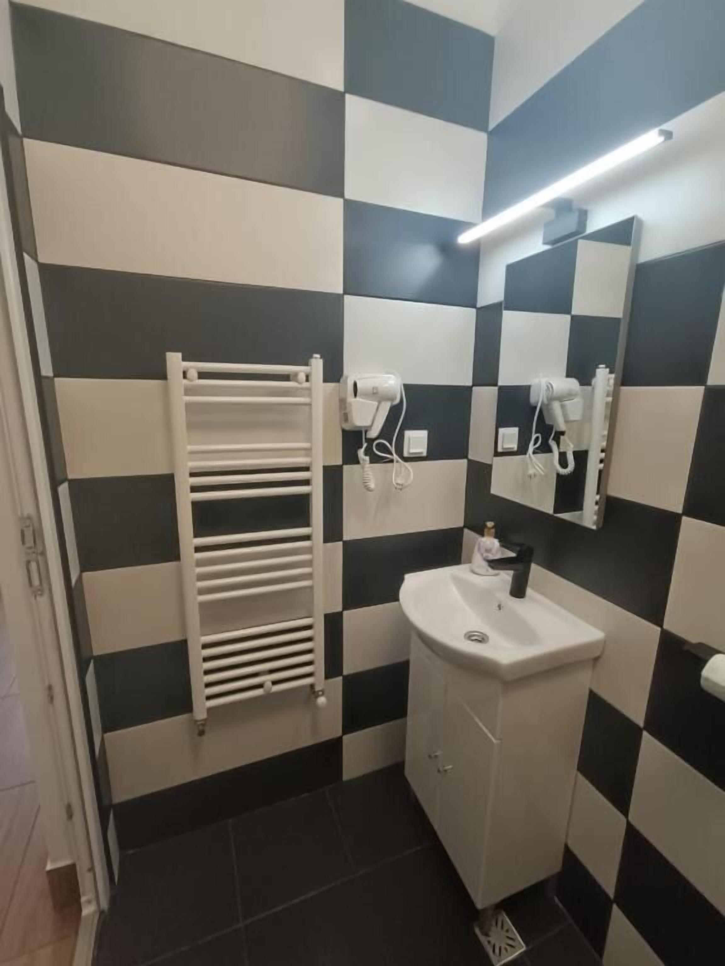 A bathroom with a checkered black and white wall pattern, a white sink, and a towel rack.