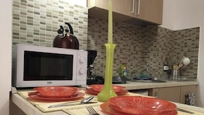 Une cuisine équipée d’un four à micro-ondes, d’une bouilloire et d’un vase vert posé sur le plan de travail.