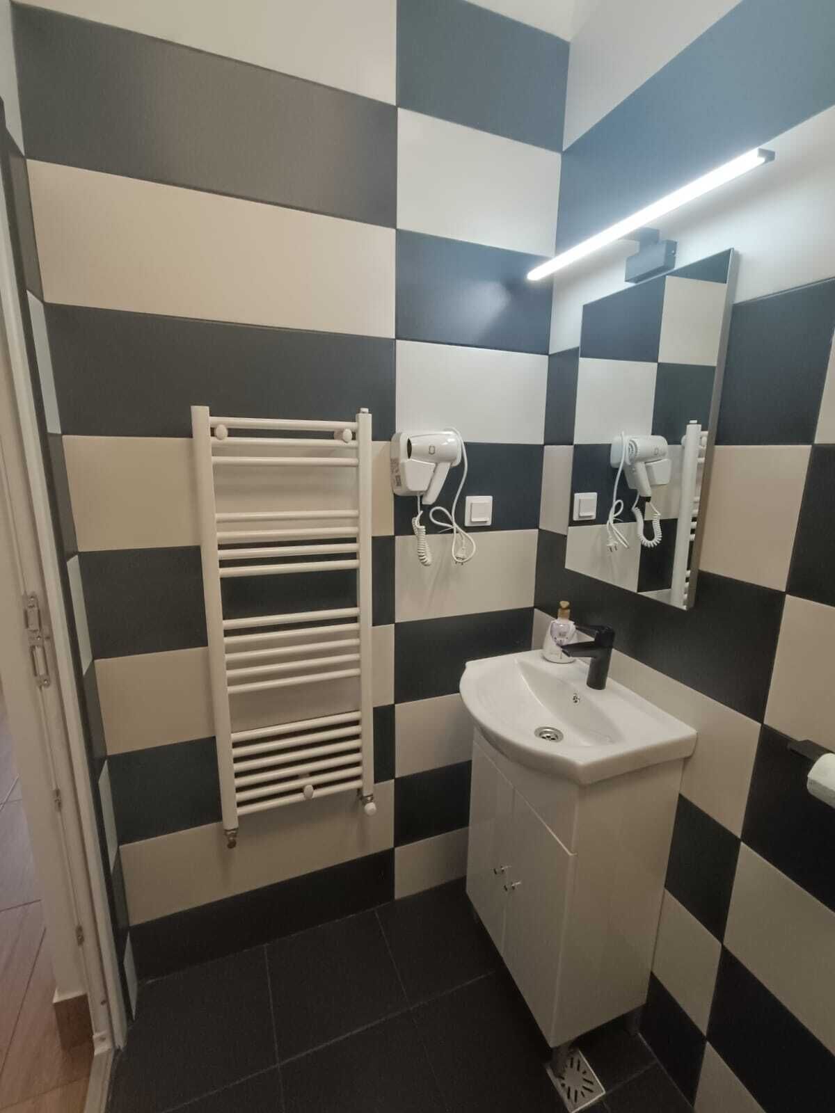 Ein Badezimmer mit Wand aus schwarz-weißen Schachfeldern, einem weißen Waschbecken und einem Handtuchhalter.