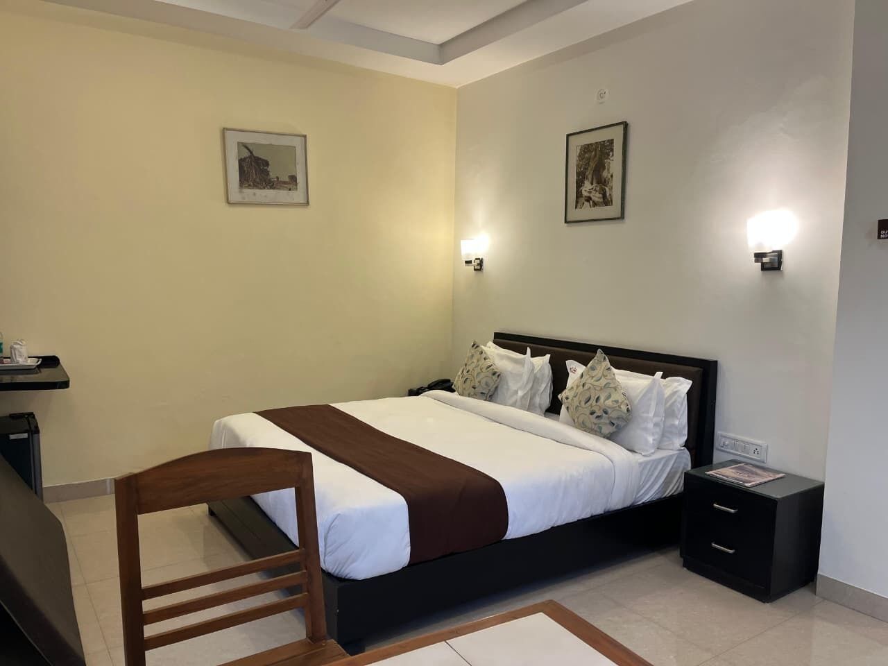 A bedroom with a bed, bedside tables, a chair, and wall-mounted lights.