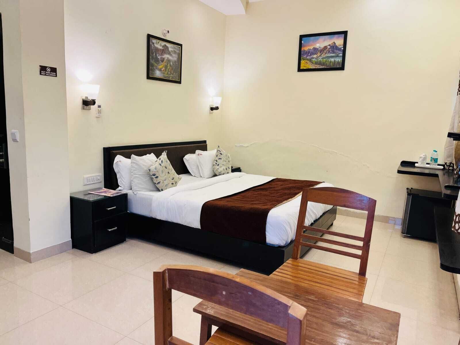 A hotel room with a bed, bedside tables, a wooden chair, and two wall-mounted lamps.