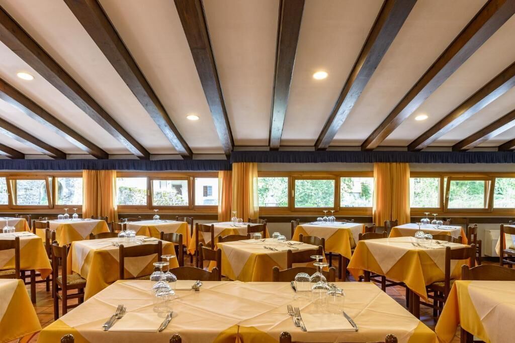 Comedor con varias mesas, cada una con mantel y cubiertos.
